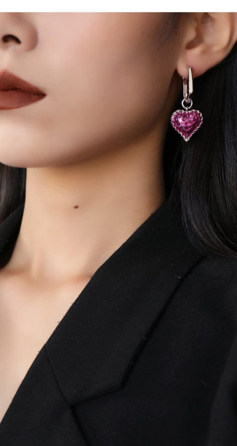 Woman wearing a black blazer with a close-up of her earring featuring a heart design.