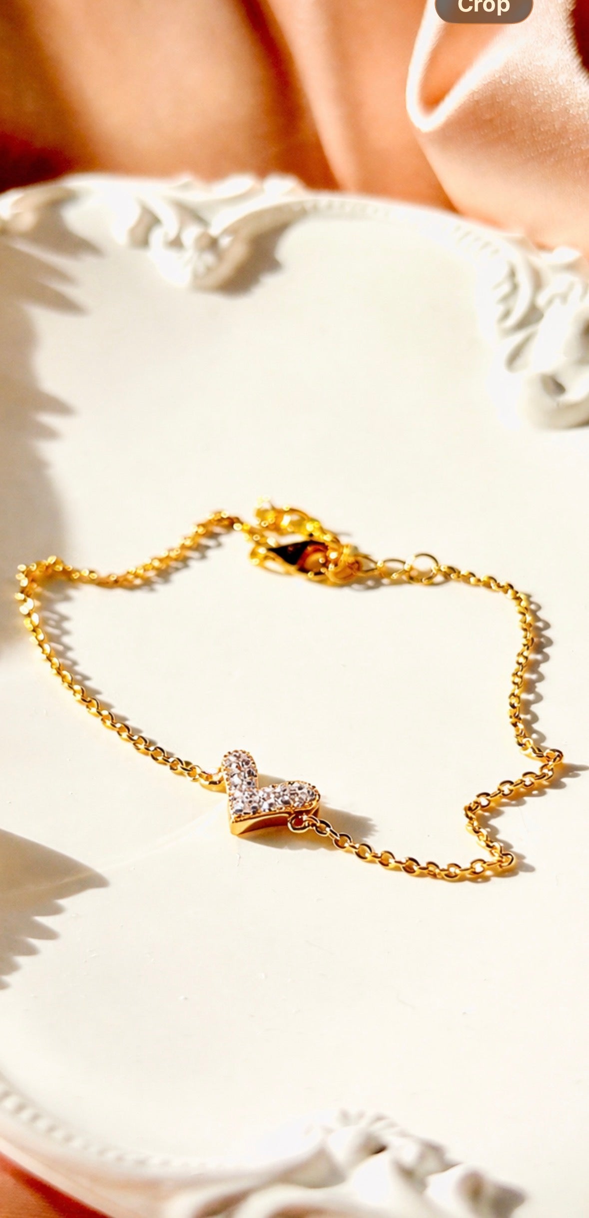 Gold bracelet with a heart charm on a white surface
